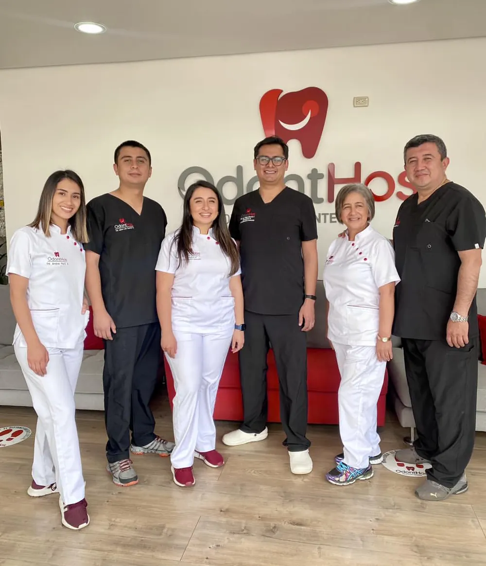 El equipo de ODONTHOS en la recepción del hospital, seis odontólogos con uniforme frente al logotipo en relieve