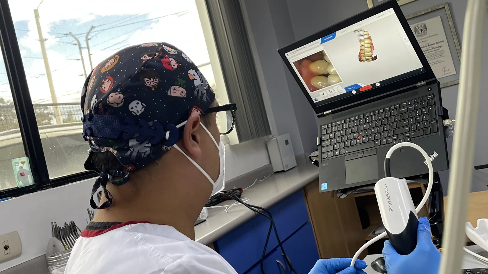 Especialista de ODONTHOS con el escáner intraoral en la mano, y el modelo de la boca del paciente en tres dimensiones en la pantalla del portátil
